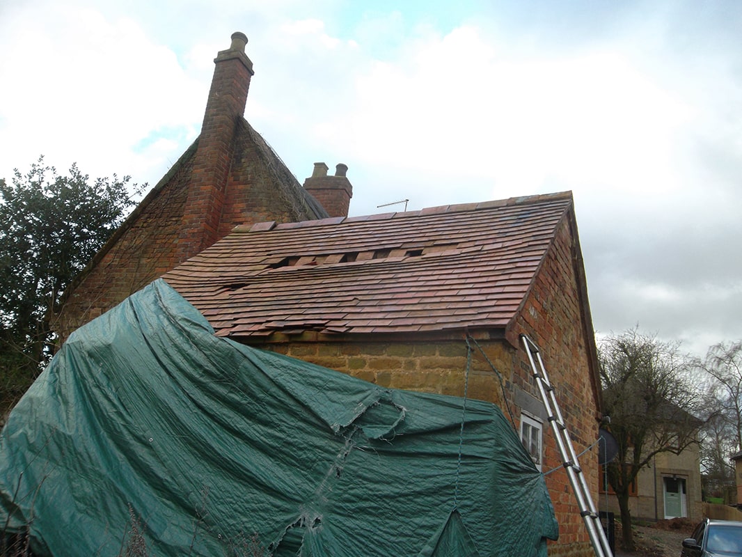 An extremely damaged tiled roof with holes